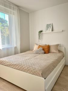 a white bed in a white room with a window at Oakwood park apartment in Kaunas