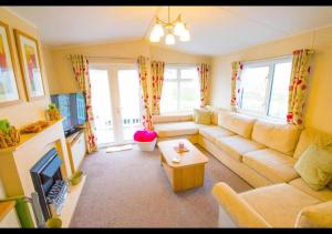 a living room with a couch and a table at MP124 - Camber Sands Holiday Park - Sleeps 6 - Full Decking - Beautiful Marsh Views in Camber