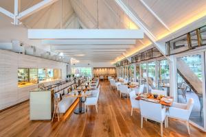 a restaurant with white chairs and tables and windows at Beach Rotana - Abu Dhabi in Abu Dhabi
