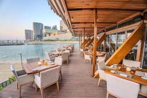 a row of tables and chairs on the deck of a restaurant at Beach Rotana - Abu Dhabi in Abu Dhabi