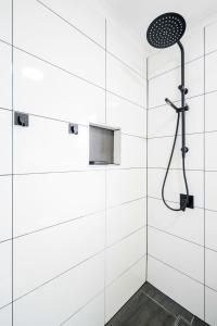 baño blanco con ducha con cabezal de ducha en Hope Cottage Tamborine Mountain, en Mount Tamborine