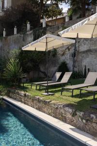 two lounge chairs and umbrellas next to a swimming pool at Au Petit Thouars in Thouars +14 photos