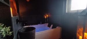 ein Bad mit einer Badewanne in der Ecke eines Zimmers in der Unterkunft "BLACQ ROOM" Luxe, balnéo, sauna 50 nuances de grey in Boeschèpe + 14 Fotos