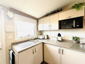 a small kitchen with a sink and a microwave at Barn Owl Lodge in Bridlington