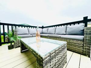 a patio with a couch and a table on a deck at Barn Owl Lodge in Bridlington