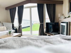 a bedroom with a bed and a tv and a window at Barn Owl Lodge in Bridlington