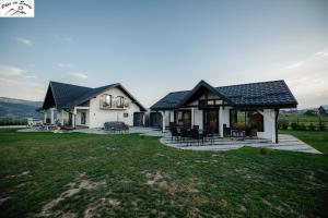 a house with a pitched roof and a patio at Casa Plai cu Soare in Vatra Dornei