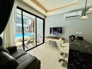 a living room with a couch and a table with a television at Poolside 1 Bedroom Apartment by Renttini in Surin Beach