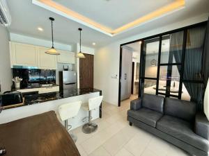 a living room with a black couch and a kitchen at Poolside 1 Bedroom Apartment by Renttini in Surin Beach