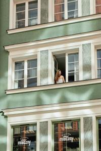 a woman is looking out of a window at Apartamenty Stągiewna by Downtown Apartments in Gdańsk