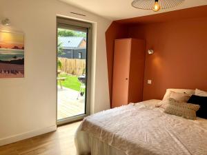 una camera da letto con un letto e una porta scorrevole in vetro di Les cabines du bout du monde - Cabine Duplex , votre maison de vacances de haut standing à Crozon a Crozon
