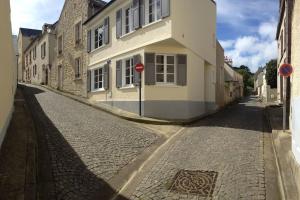 a street with a building and a stop sign at Le Baluchon Portais - Gîte de Charme in Port-en-Bessin-Huppain