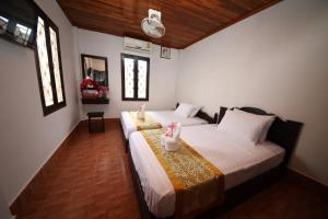 a bedroom with two beds and two windows at Nirasim Villa in Luang Prabang