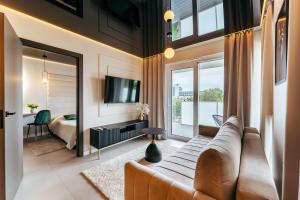 ein Wohnzimmer mit Sofa und ein Schlafzimmer in der Unterkunft Apartamenty z Jakuzzi Perłowa Przystań Rent Kołłątaja in Kołobrzeg