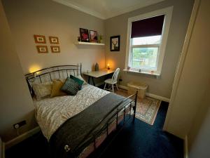 a bedroom with a bed and a table and a window at Stylish and artistic flat in Southend on Sea in Southend-on-Sea