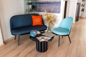 a living room with a blue chair and a table at Best Western Hôtel Royan Océan in Royan