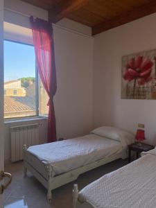 a bedroom with two beds and a large window at Casa campo della fiera in San Lorenzo Nuovo