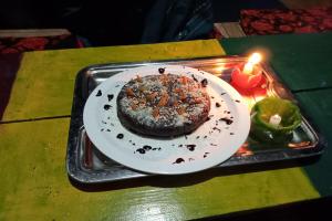 a cake on a tray on a table with a candle at Hotel O Snow Pine Guest House Tosh in Manīkaran