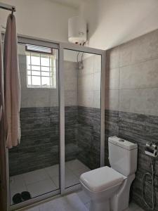 a bathroom with a toilet and a shower at Alsander Homes Raspberry in Kampala +13 photos