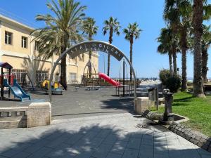 a playground with a slide in a park with palm trees at Gaia Home by Holiday Home in Loano +14 photos