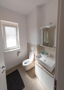 a white bathroom with a toilet and a sink at Modern Chic Apartment - near Iulius Mall in Timişoara