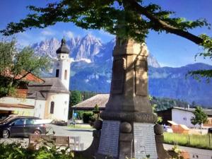 a church and a tower with a mountain in the background at Appartement Foidl mit Kaiser & Hornblick in Oberndorf in Tirol