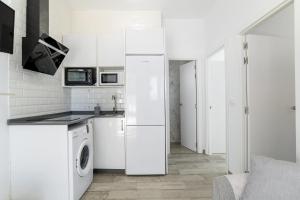 a white kitchen with a refrigerator and a washer and dryer at Apartamento La esencia del sur A in Vejer de la Frontera