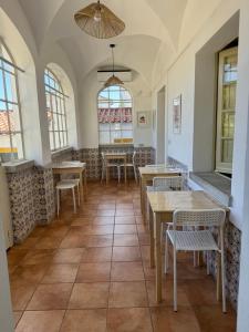 Un restaurante con mesas, sillas y ventanas. en T'Inácia Guest House, en Évora