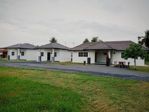 a row of white houses with a gravel road at Banat Village Stay in Arau