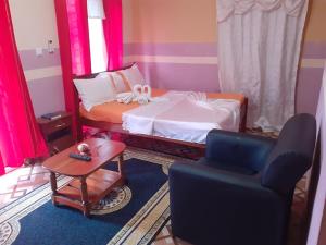 a bedroom with a bed and a chair and a table at Residencial - AEMANUEL in São Tomé