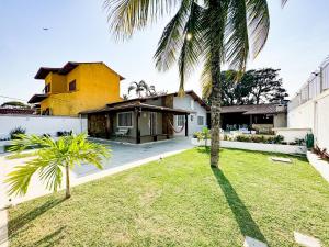 a house with a palm tree in the yard at Casarão e piscina localização excelente | ROSF91 in Rio das Ostras