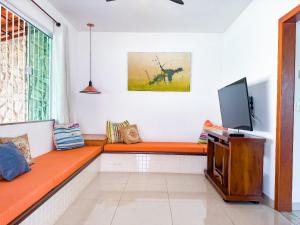 a living room with an orange couch and a flat screen tv at Casarão e piscina localização excelente | ROSF91 in Rio das Ostras