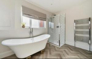 a white bath tub in a bathroom with a shower at Freshly decorated 2 bedroom apartment 10 mins from Cotswolds Child Friendly Great location with plenty of nearby free parking freestanding bath and outdoor private terrace area in Evesham +27 photos