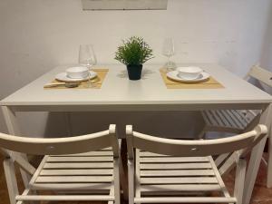 Una mesa blanca con dos sillas y dos vasos y una planta. en Vive Huelva MARINA WIFI 300 VFTHU01194, en Huelva