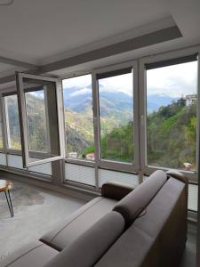 a living room with a couch in front of windows at Melikoğlu Suite in Dernekpazarı