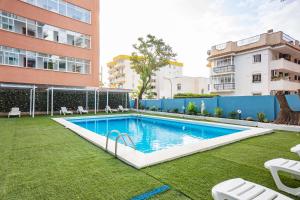 a swimming pool in a yard next to a building at Apartamentos El Velero in Torremolinos