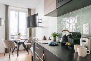 Una cocina con encimera y mesa con sillas. en République - Charmant studio - Haystia, en París