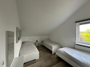 two beds in a white room with a window at Big Family villa 12p big garden with bathtub and jacuzzi in Zeewolde +17 photos