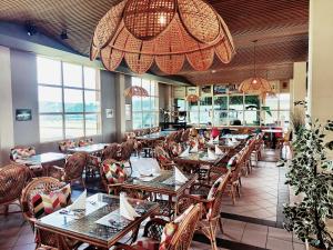 a restaurant with wooden tables and chairs and windows at Le Relais de la Croisée in Malvilliers