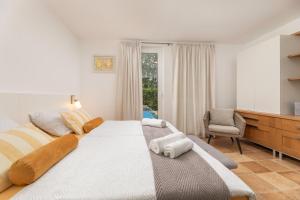 a bedroom with a large white bed and a chair at Apartman Fana in Njivice