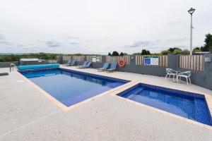 a swimming pool on a patio with two chairs around it at The Milking Parlour in Aberystwyth