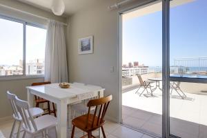 een woonkamer met een tafel en stoelen en een balkon bij Cond. Isola Ravenna - Ingleses Norte in Florianópolis