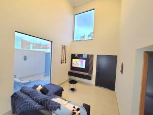 a living room with a couch and a tv at Linda casa a 200m da Praia do Capricórnio in Massaguassu