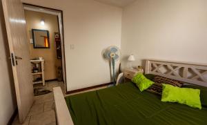 a bedroom with a green bed and a fan at Umi del sur in Mar del Plata