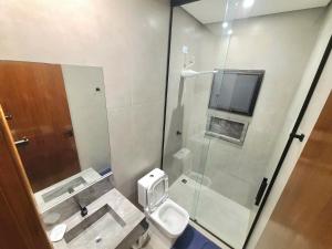 a bathroom with a toilet and a glass shower at Linda casa a 200m da Praia do Capricórnio in Massaguassu +19 photos