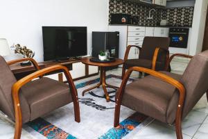 een woonkamer met 2 stoelen, een tafel en een televisie bij Appartement 2pièces et terrasse in Abidjan
