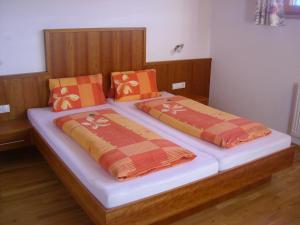 2 Betten mit orangefarbenen und orangefarbenen Kissen darauf in der Unterkunft Haus Neurauter in Niederthai