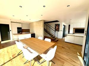 a kitchen and dining room with a wooden table and white chairs at Maison neuve - Piscine chauffée - Erdeven in Erdeven
