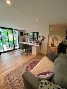 Una sala de estar con un sofá y un escritorio. en Chambre Atelier sur jardin, en Antony