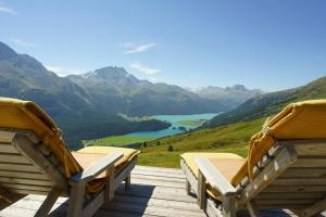 two chairs on a deck with a view of a mountain at Suvretta House in St. Moritz